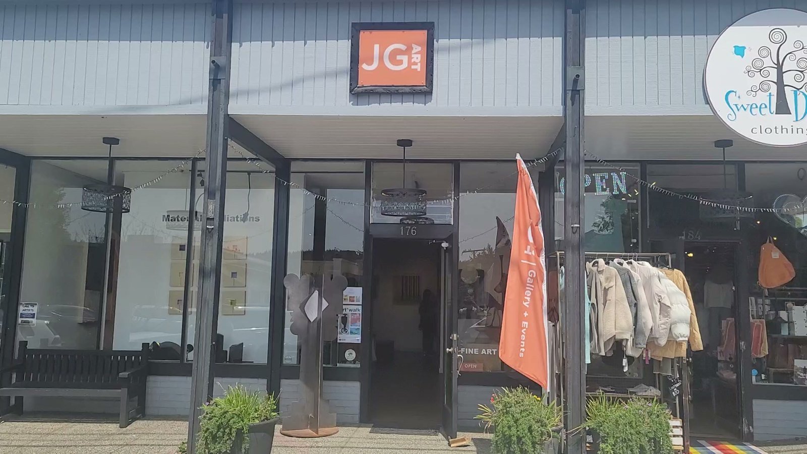 JG Art Gallery storefront at 176 Winslow Way, Bainbridge Island - orange JG ART sign, open flag and planters